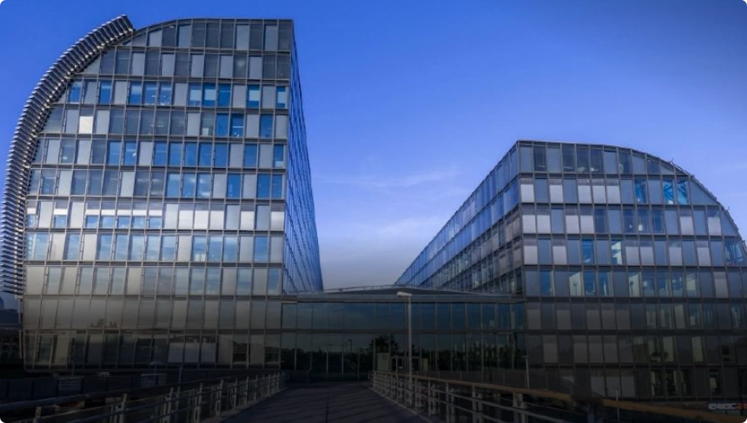 Full shot of Rivergate building in Austria. The building is unique, and feature two oval shaped offices. The windows are navy and grey and shimmer in the light.