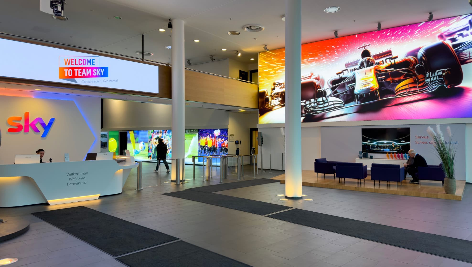 Sky reception area with colorful digital displays and a bold racing graphic on the wall.