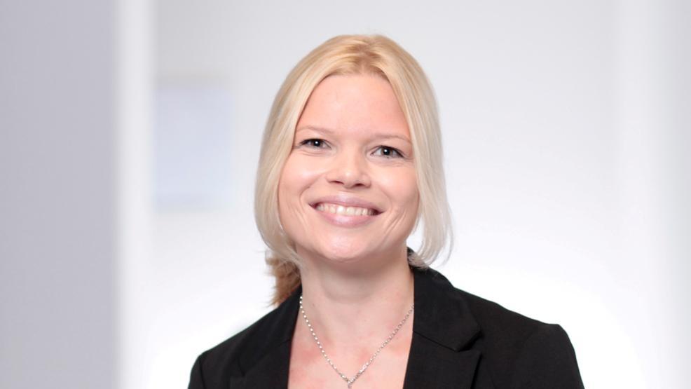 A professional profile picture of Katharina - in front of a bright office background.
